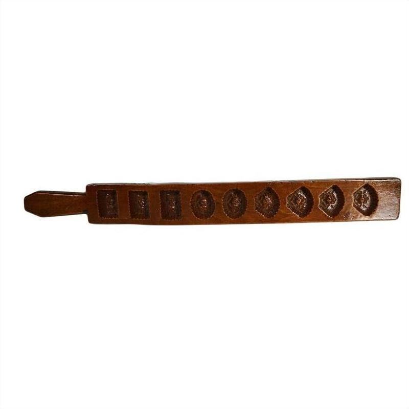 Brown wooden antique Chinese rice mold with seven rectangular motif carvings, close-up on plain background.