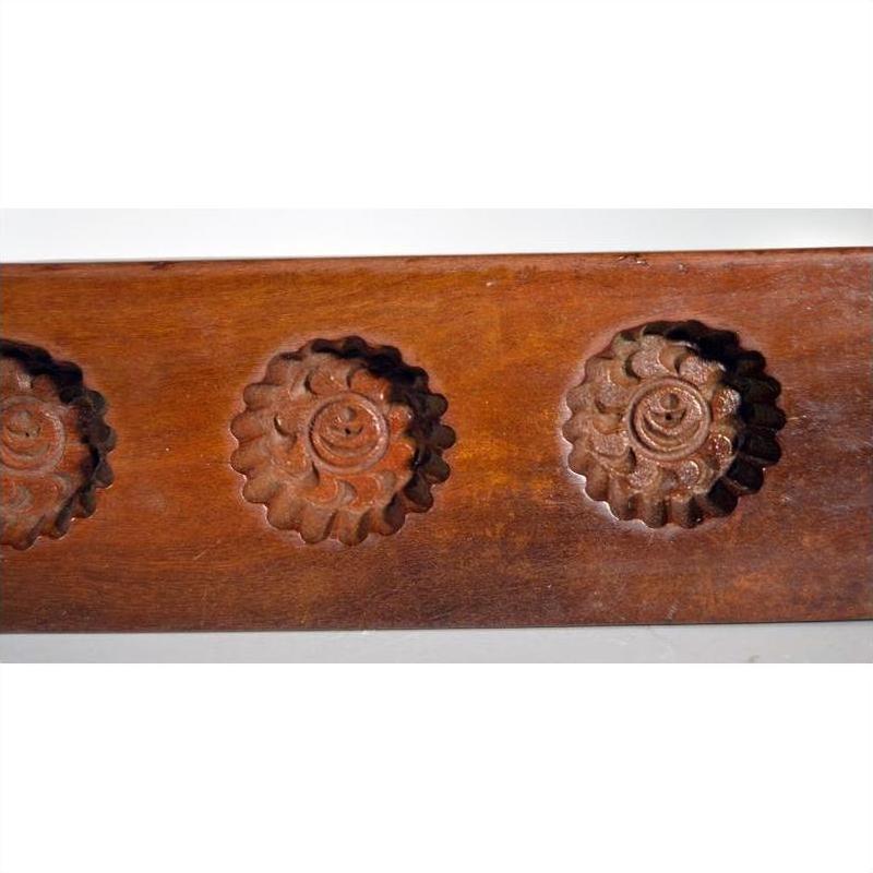 Close-up of dark wood antique Chinese rice mold with five spiral floral cavities.