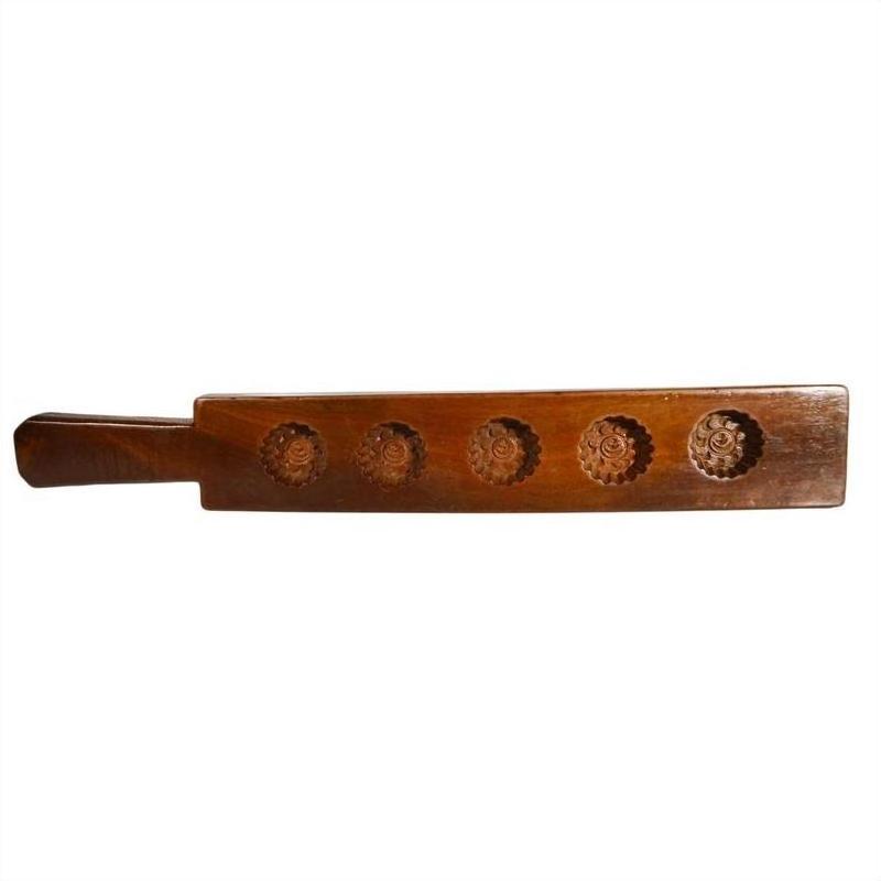 Brown antique wooden Chinese rice mold with five spiral floral cavities and side handle on a white background.