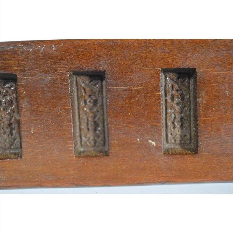 Close-up of brown antique wooden Chinese rice mold with six rectangular motifs and incised characters.