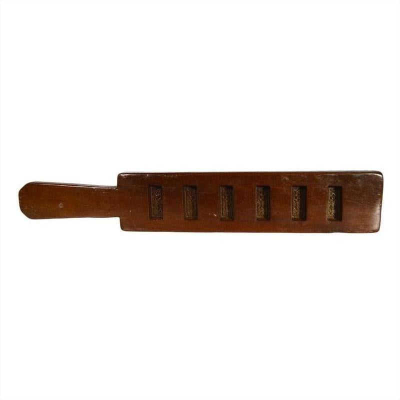 Close-up of antique Chinese rice mold, carved wood with six rectangular motifs and incised Chinese characters.