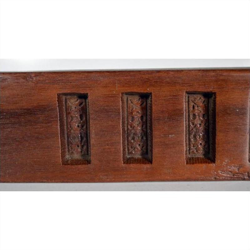 Brown wooden antique Chinese rice mold with six character cavities, curved paddle shape, close-up on plain background.