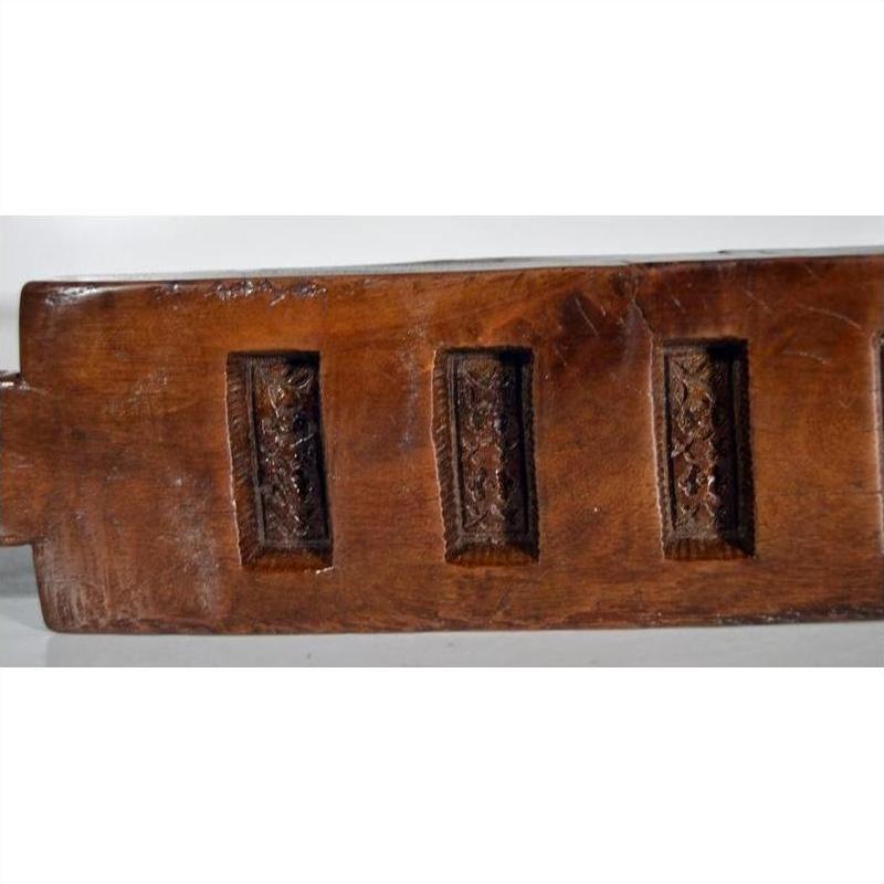 Dark wood antique Chinese rice mold with six rectangular seal carvings, close-up view.
