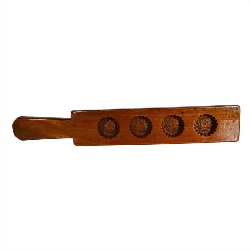 Close-up of solid walnut antique Chinese rice mold paddle featuring four carved floral molds on wood surface.