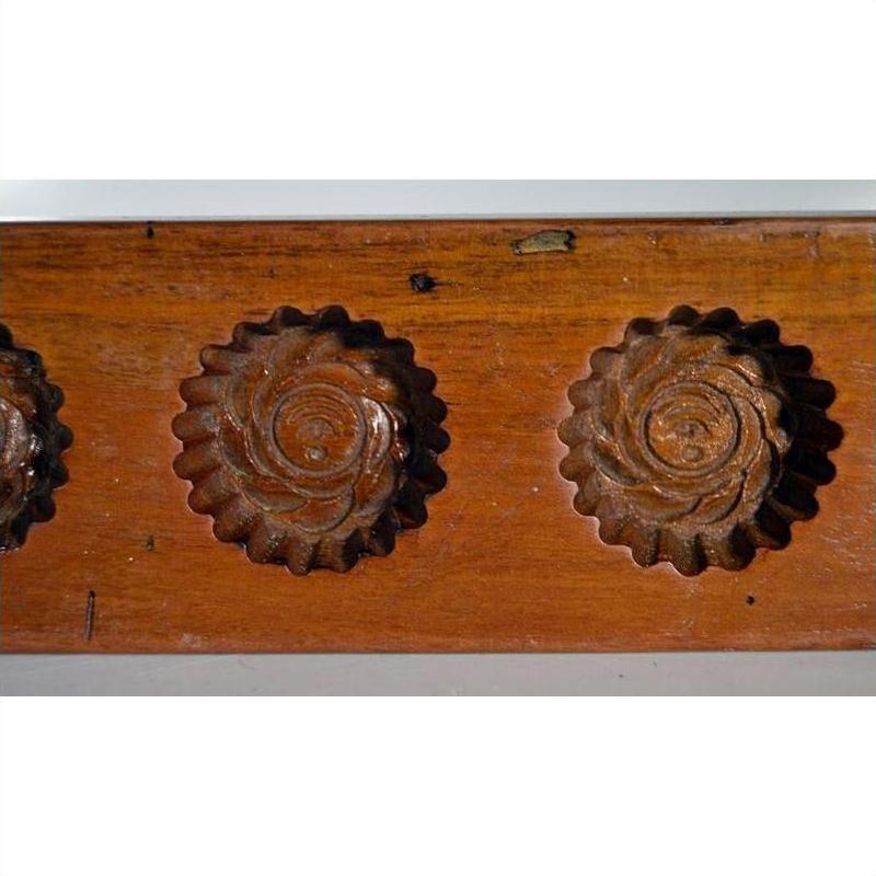 Close-up of antique walnut-finish Chinese rice mold paddle with two round floral cavities, solid wood.