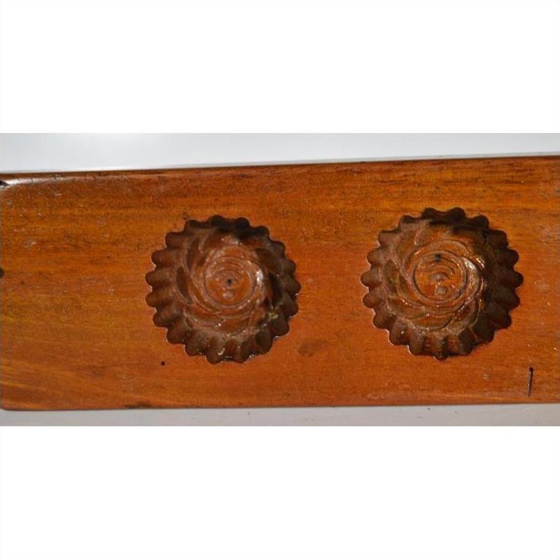 Close-up of walnut-finished antique Chinese rice mold with floral carvings, additional models in background.