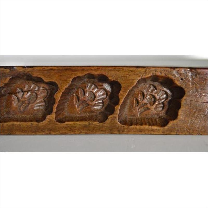 Close-up of brown antique wooden Chinese rice mold with five carved symbol cavities, used for decor or printing.