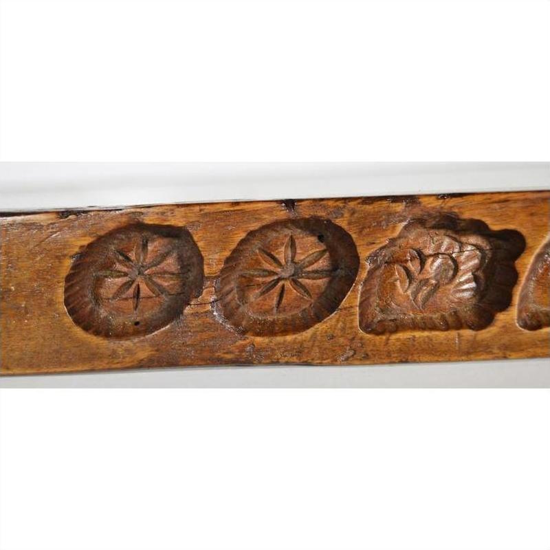 Close-up of a brown antique wooden Chinese rice mold with five cavities, carved star and heart designs.