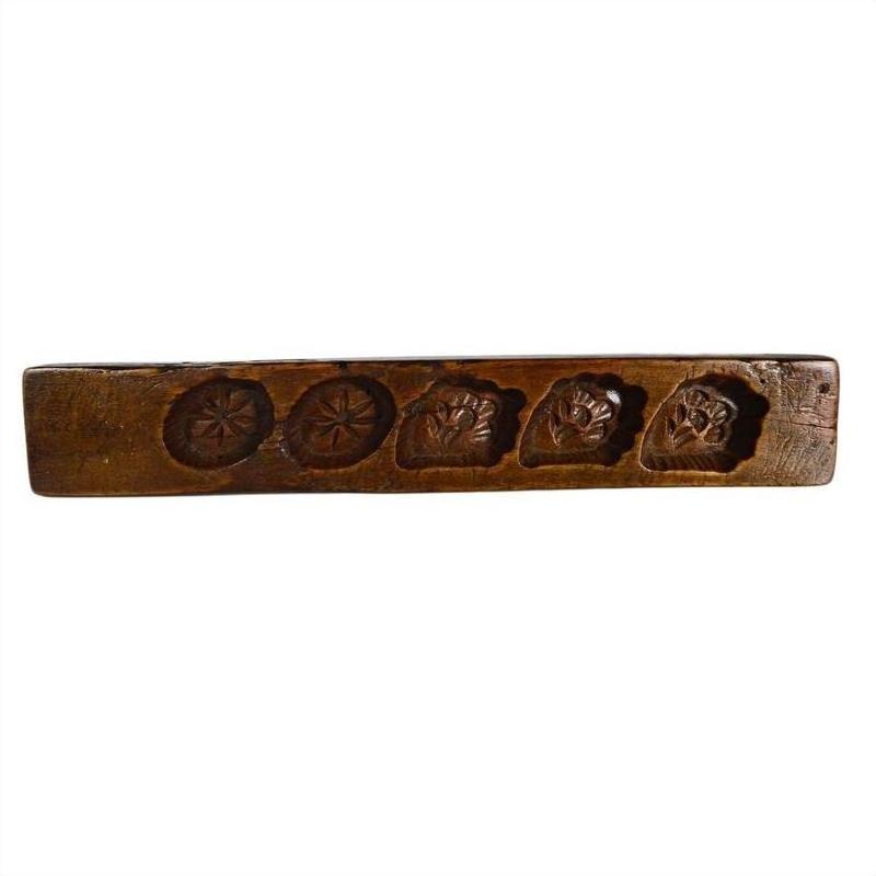 Brown wooden antique Chinese rice mold with five uniquely carved symbol cavities, close-up view.