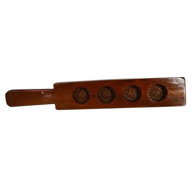 Brown wooden antique Chinese rice mold with long handle and four round rosette cavities, close-up on plain surface.