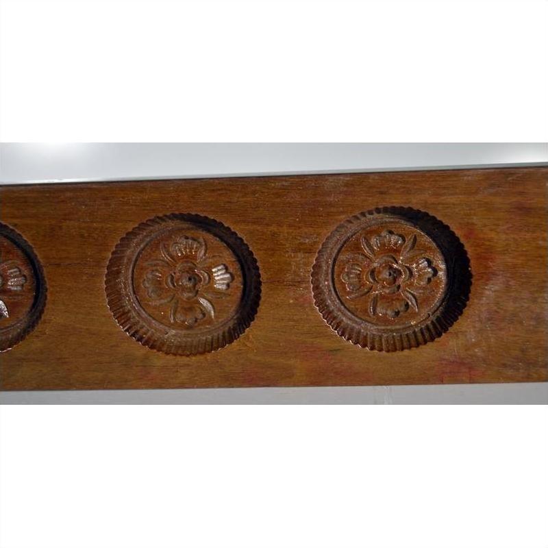 Close-up of antique Chinese rice mold, carved wood, four round seal cavities with calligraphy detail.