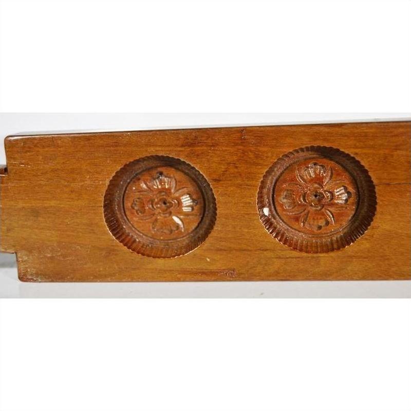 Close-up of a brown antique Chinese rice mold, wood material, with four round seal cavities and intricate calligraphy detail.