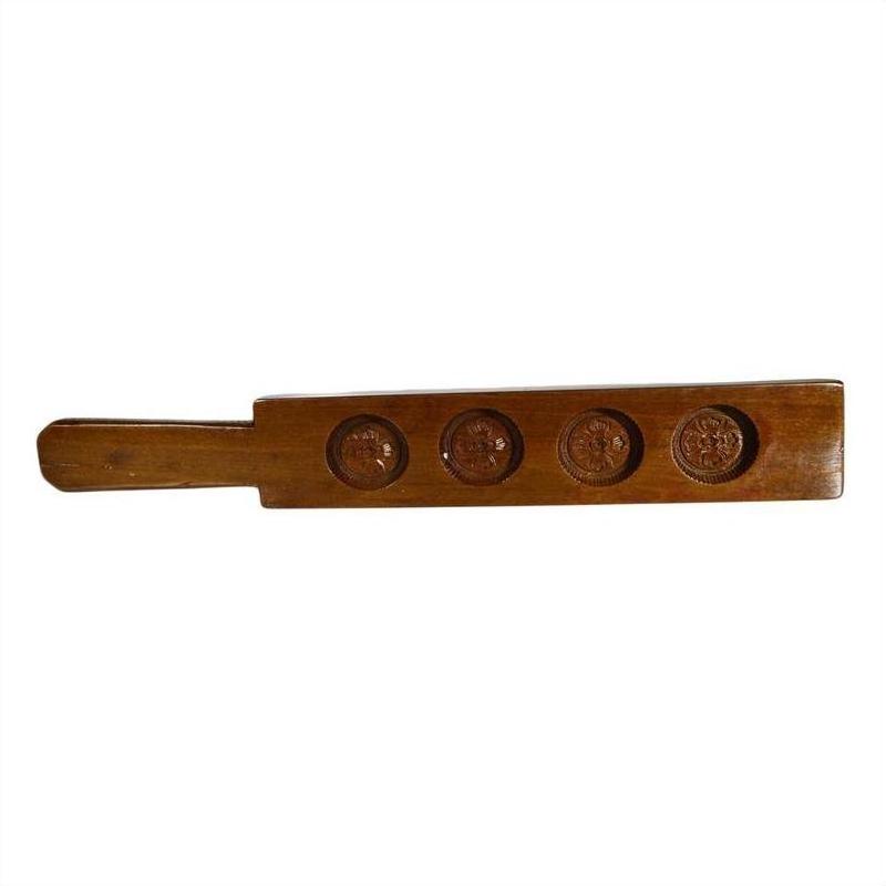 Brown wooden antique Chinese rice mold with four round seal cavities and engraved calligraphy, close-up on white surface.