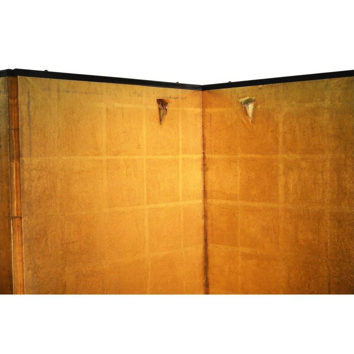 Beige and yellow wall with two small triangular metal fixtures next to an antique Chinese screen.