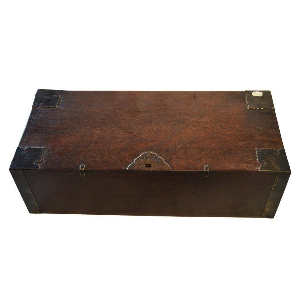 Brown wood antique Chinese chest with metal corner brackets and front keyhole, close-up on rectangular box.