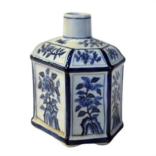 White porcelain sake bottle with blue hand painted floral designs, hexagonal shape, and narrow neck, close-up.