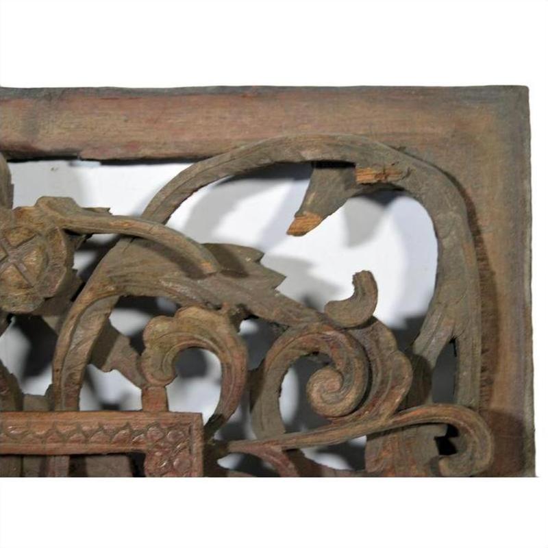 Close-up of brown wood antique Chinese temple carving with ornate floral and scroll patterns, intricate details visible.
