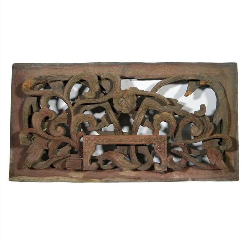 Brown wooden rectangular panel with intricate floral and vine carvings, antique Chinese temple art, close-up.