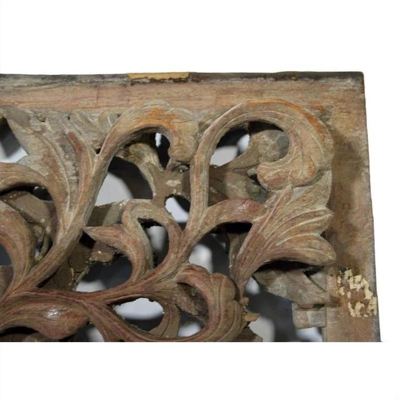 Close-up of weathered wood antique Chinese temple carving with intricate floral and leaf motifs.