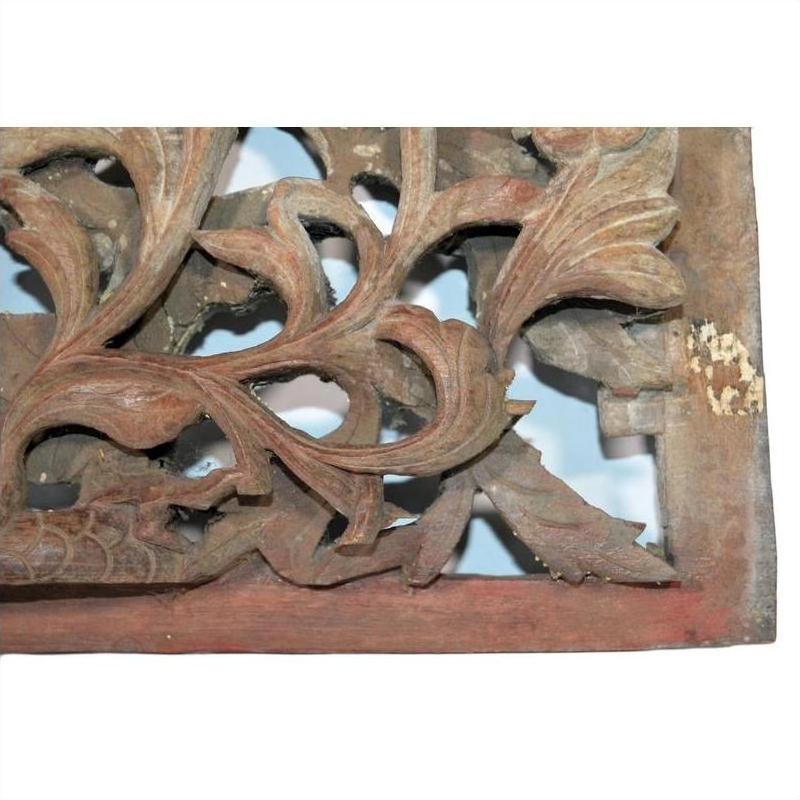 Close-up of aged wood Chinese temple carving with ornate floral details, antique finish visible.