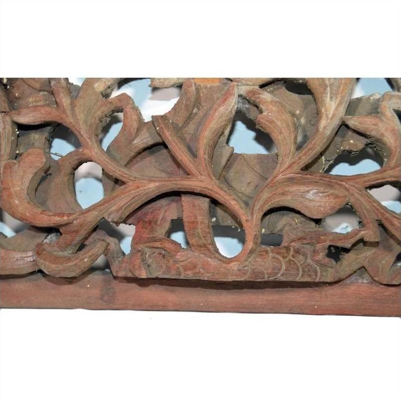 Light wood panel with intricate leaf and vine carving, antique Chinese temple art, close-up view.