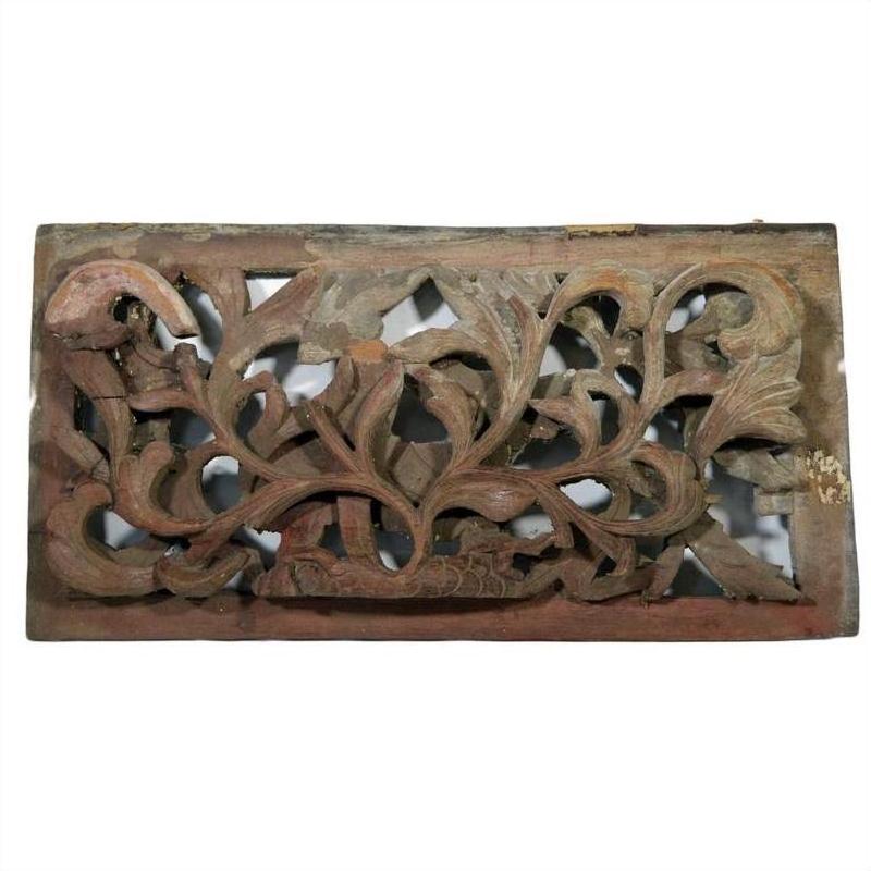 Close-up of a weathered brown wooden panel with intricate floral and leaf carvings, antique Chinese temple art.