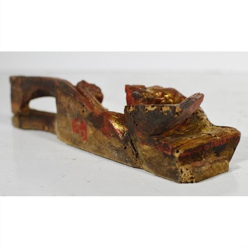 Close-up of worn gold and red wooden reclining figure, antique Chinese temple carving with visible weathering.