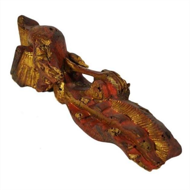 Close-up of antique wooden reclining figure with gold and red paint, weathered texture, Chinese temple carving.