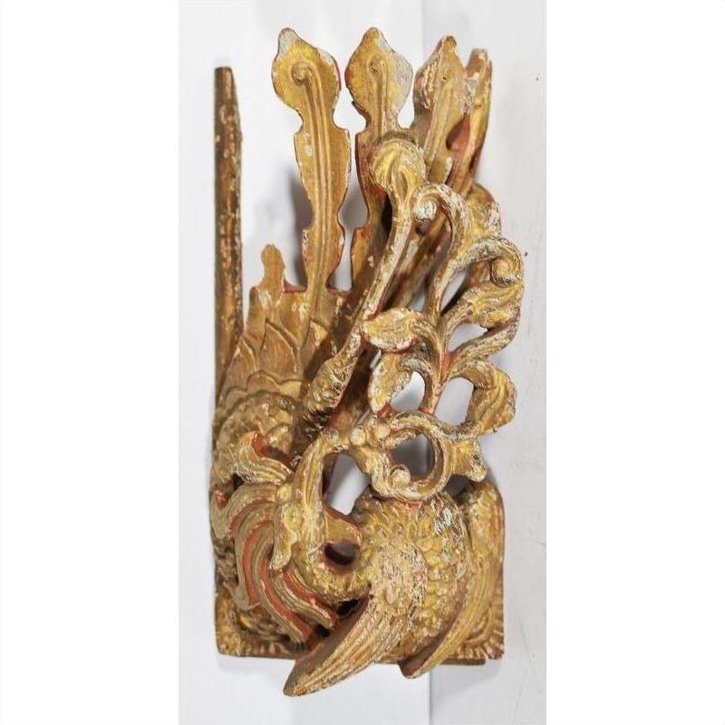 Close-up of antique Chinese temple carving in ornate red and gold wood, with stylized bird and detailed feathers.