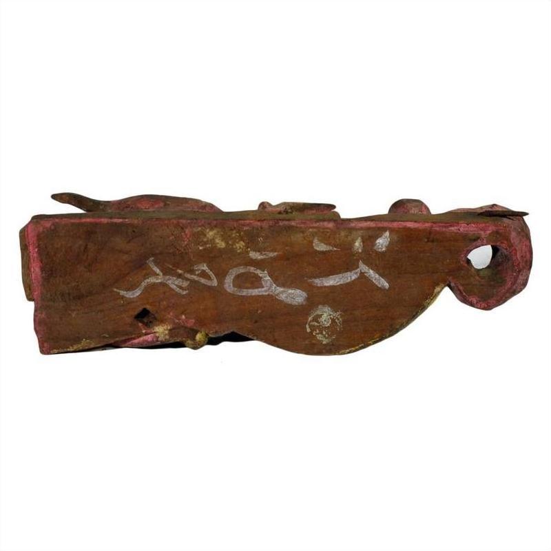 Brown carved and painted wood Chinese temple carving with white markings, hole on one end, natural light setting.