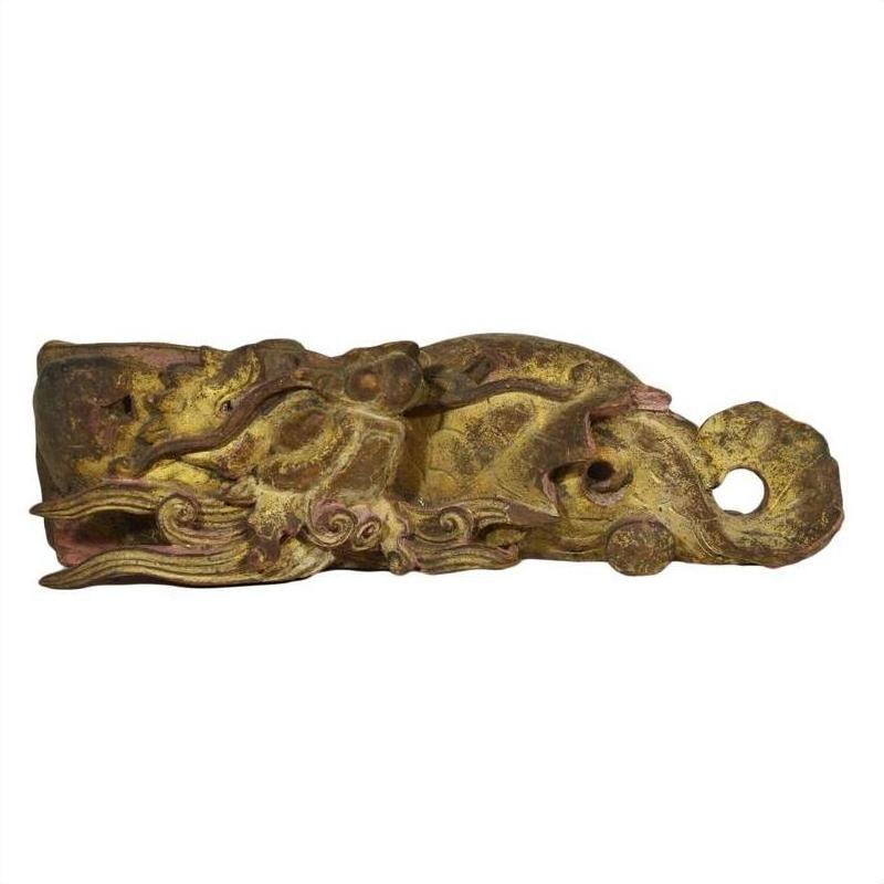 Close-up of gold and brown wooden temple carving featuring intricate, stylized dragon design.