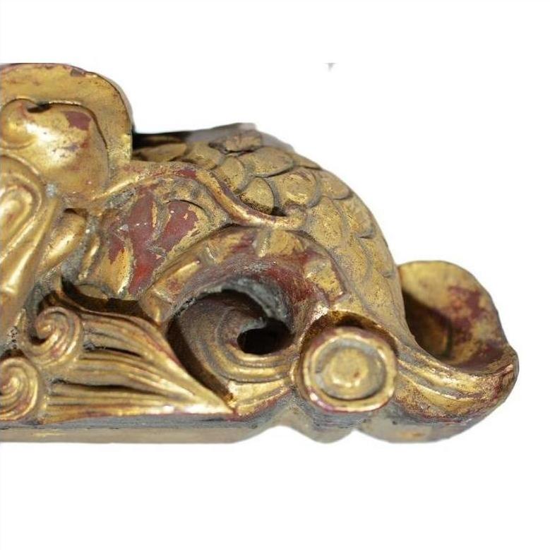Close-up of gold and red antique Chinese temple carving with ornate swirling, scale-like traditional patterns.