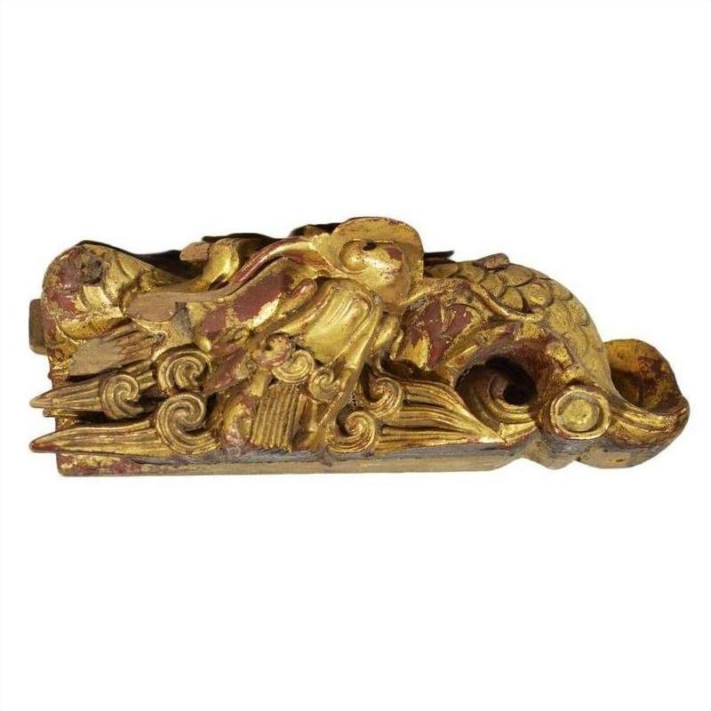 Close-up of gold and red wooden bird sculpture with ornate swirling patterns, antique Chinese temple carving.