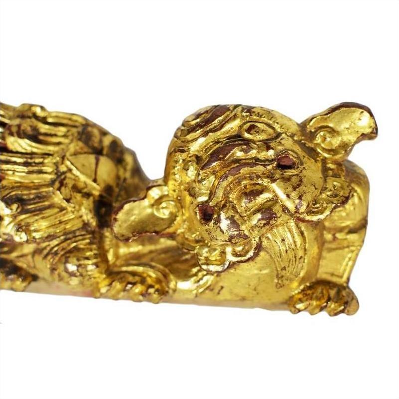 Close-up of gold-colored carved wooden dragon figures with red eyes, ornate design, pair shown together.