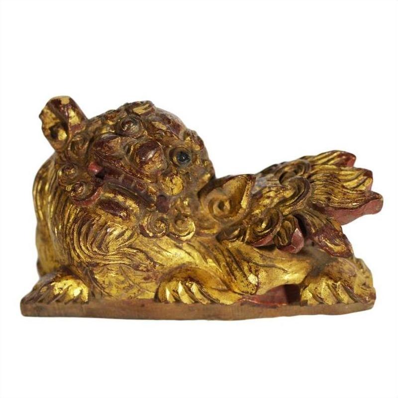 Gold and red antique Chinese dragon temple carving with detailed mane, lying down, one paw raised, close-up view.