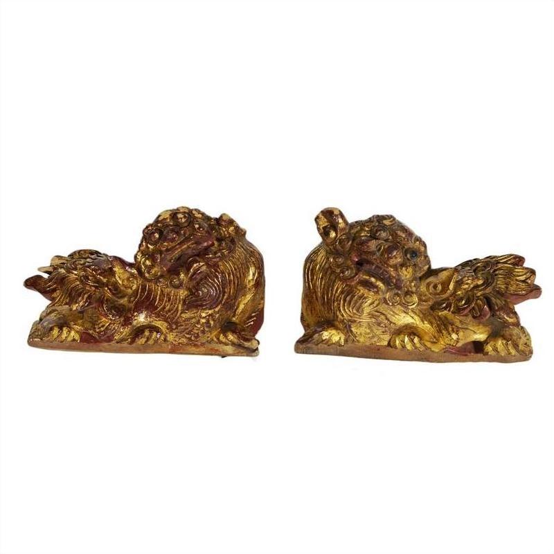 Close-up of gold-tone dragon-shaped antique Chinese temple carvings with intricate details, facing each other.