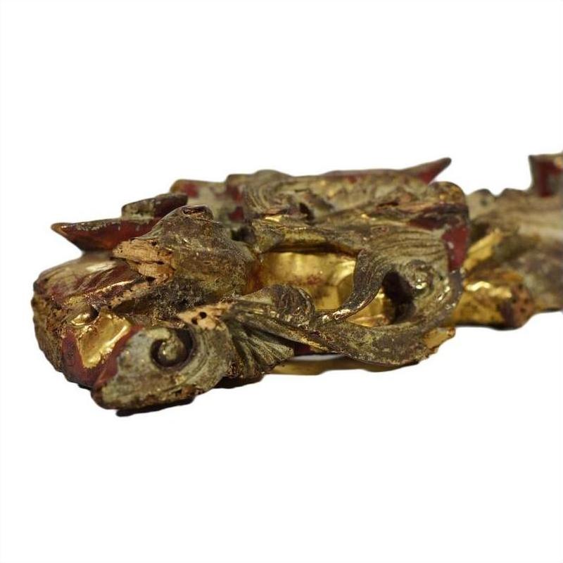 Close-up of gold and red wood Chinese temple carvings pair with ornate scroll and leaf patterns.