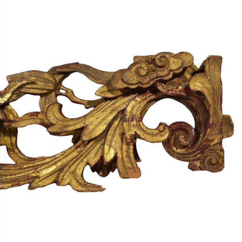 Gold and red wood antique Chinese temple carvings with intricate leaf and scroll patterns, close-up view.