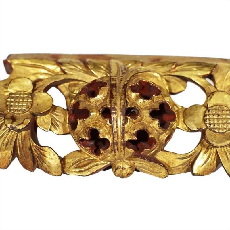 Gold wood Chinese temple carvings with ornate floral motifs, round pierced centers, and detailed leaf designs, close-up.