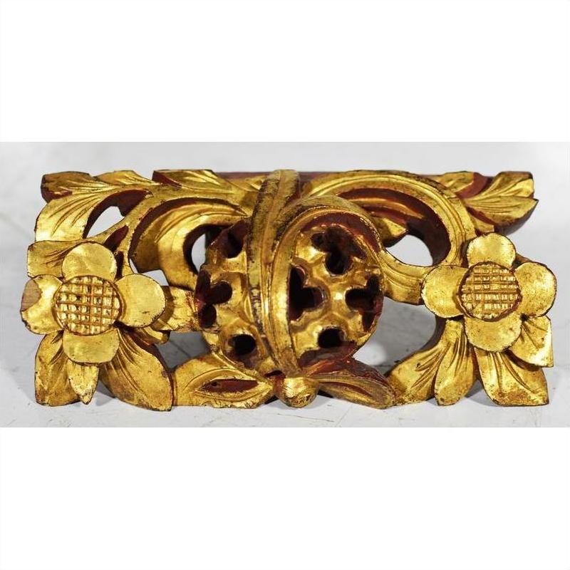 Close-up of gold-painted wood Chinese temple carvings with floral and leaf motifs and a central medallion.