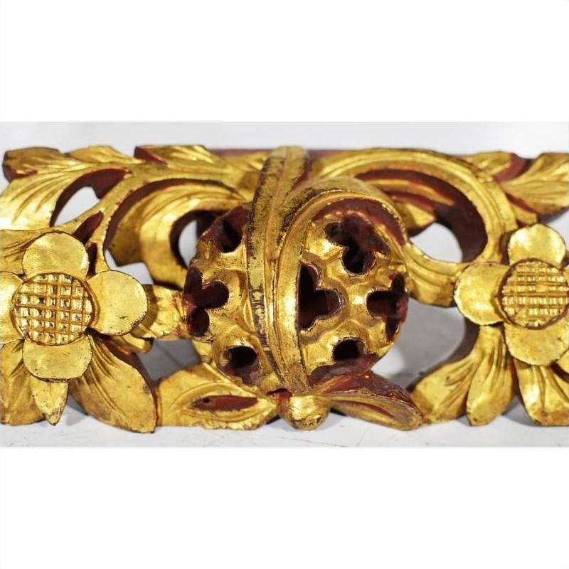 Brown wood temple carvings with floral motifs, intricate patterns, and central round accent, side by side indoors.