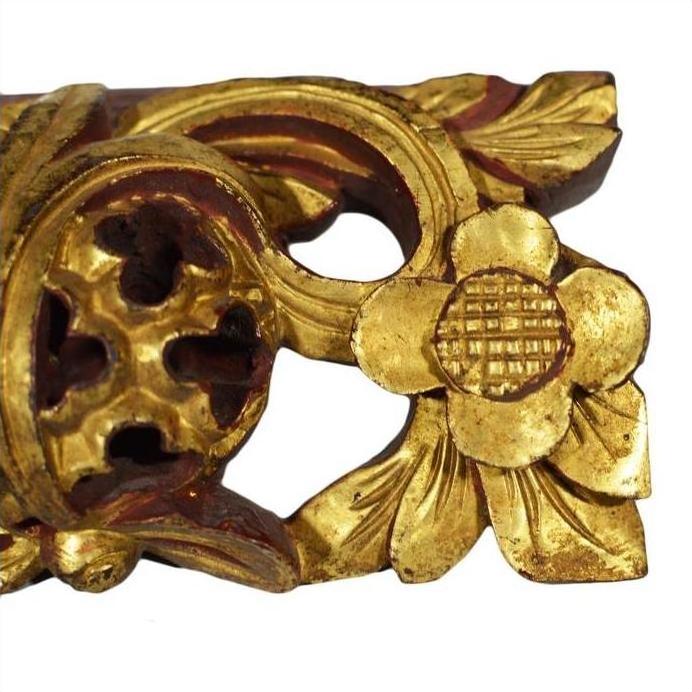 Close-up of gold-painted wood temple carvings with intricate floral and leaf designs, pair displayed together.
