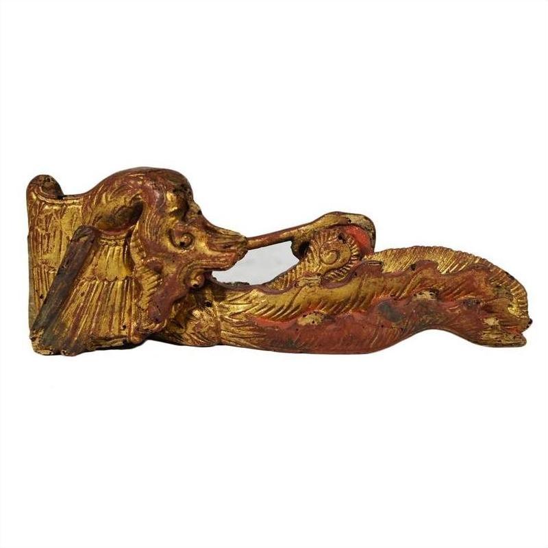 Close-up of ornate gold and red wood Chinese temple carvings featuring stylized animal head designs.