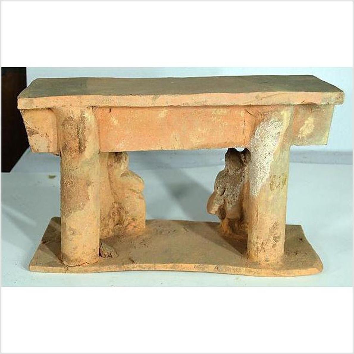 Brown terracotta Chinese town gate with two thick columns and small partial human figures beneath, 17th century.