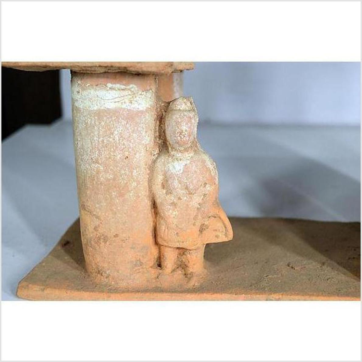 Brown terracotta town gate with small figure and cylindrical column, 17th century Chinese, museum display setting.