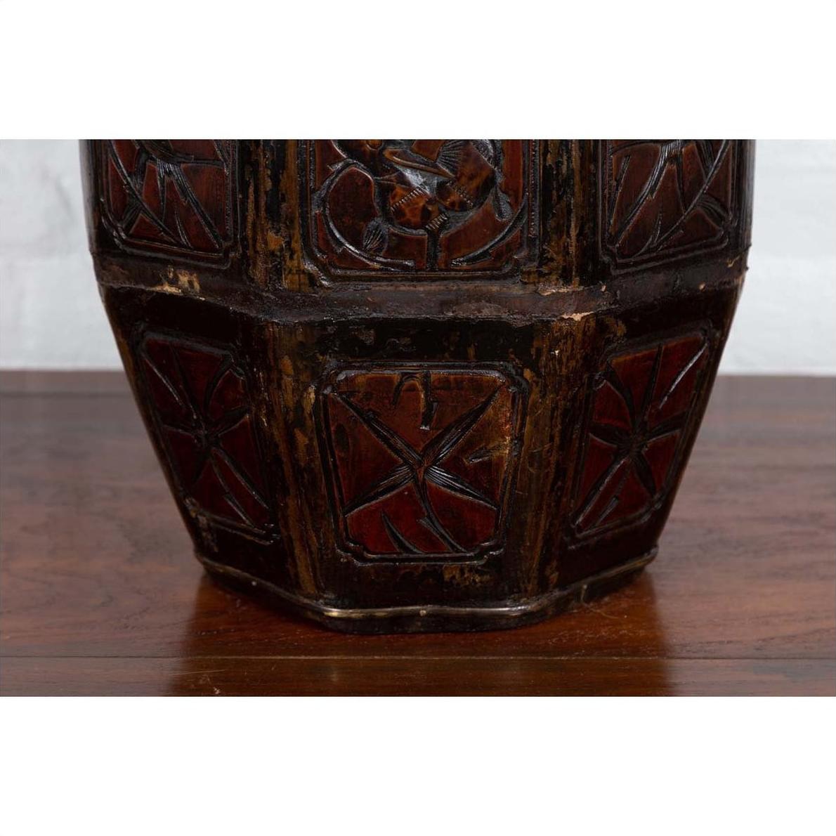 Close-up of a brown wooden antique Chinese wedding box with carved handle, animal and foliage motifs on a wooden surface.