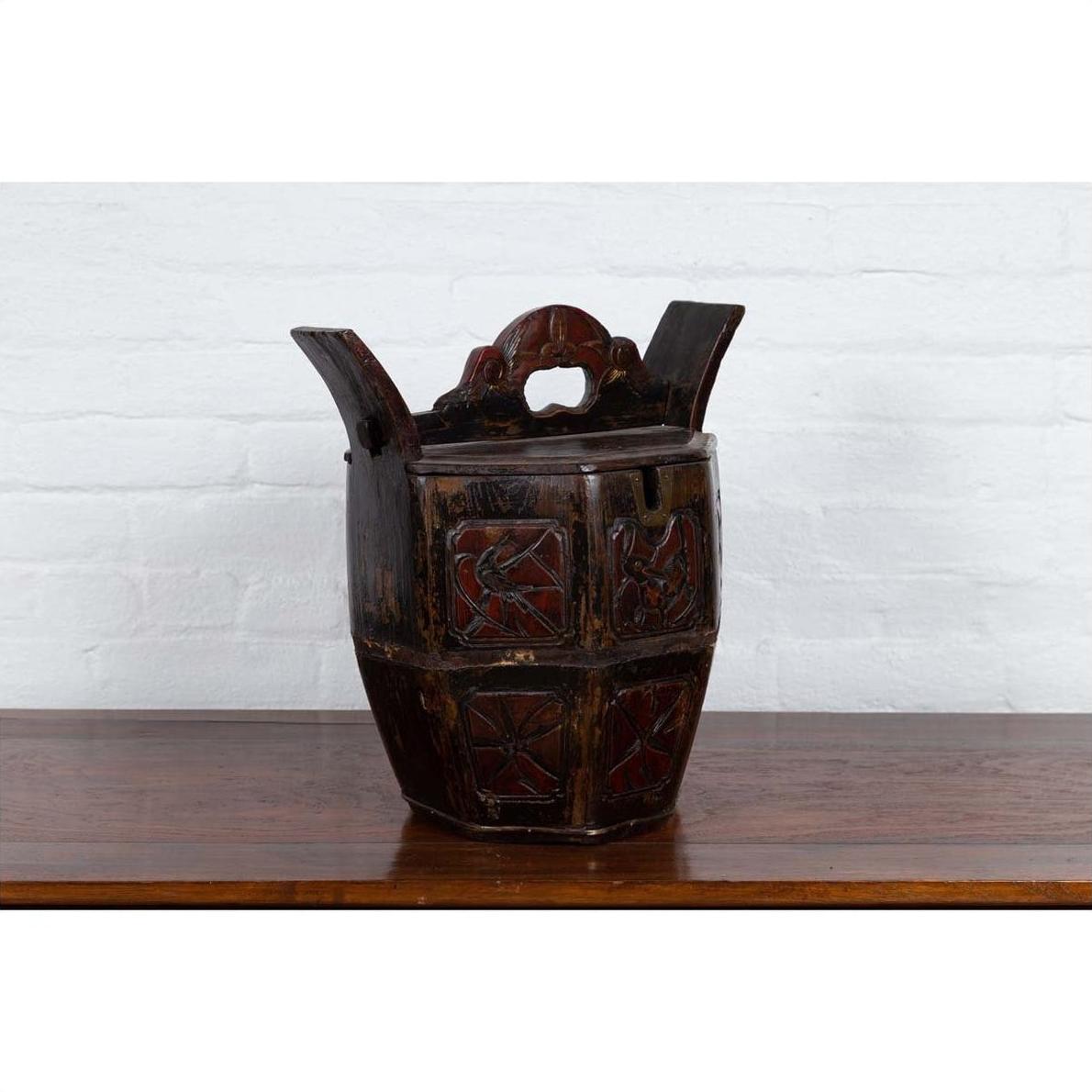 Brown wooden antique box with carved handle, animal and foliage motifs, on a wooden table indoors.
