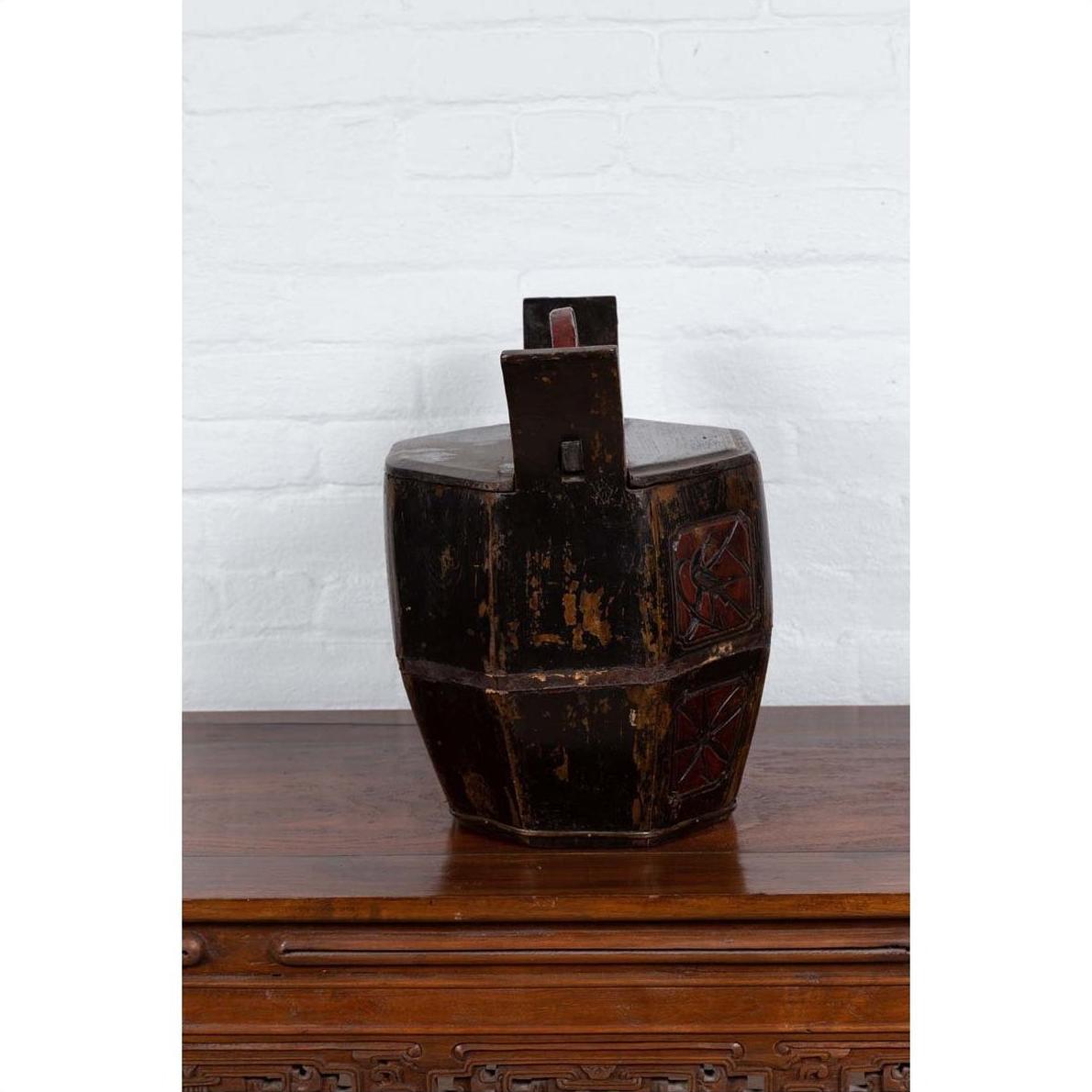 Brown wooden Chinese wedding box with carved handle, animal and foliage motifs, on table by white brick wall.