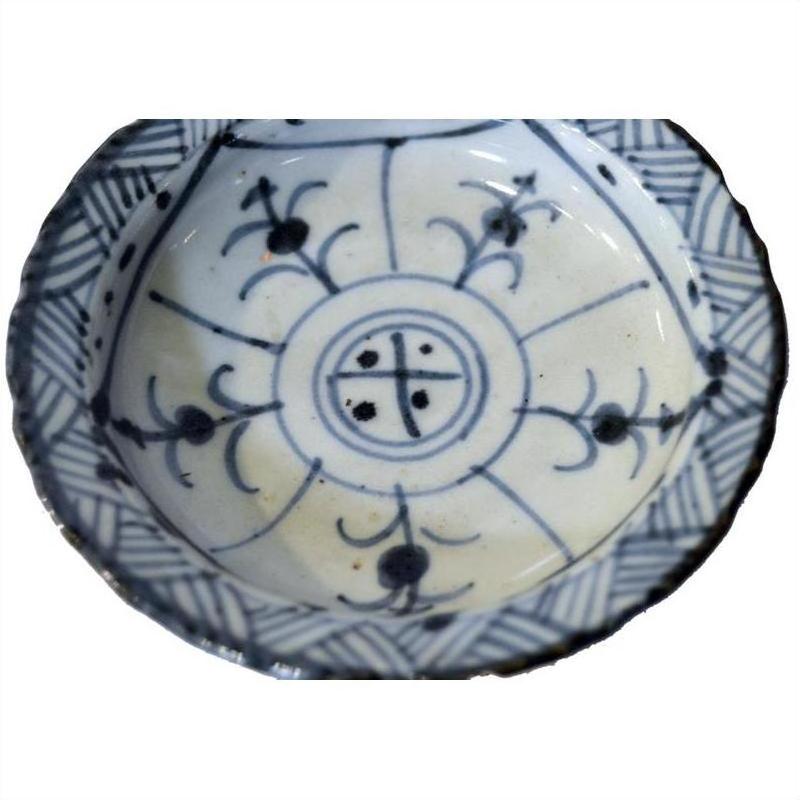 Close-up of antique Chinese blue and white ceramic footed rice bowl with floral and geometric patterns.