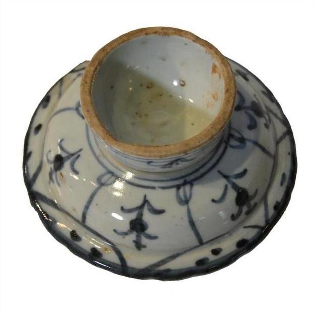 Close-up of an antique Chinese white and blue ceramic footed rice bowl upside down, showing base and blue floral design.